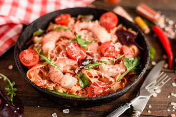 Tasty pasta with shrimp and tomato on a frying pan