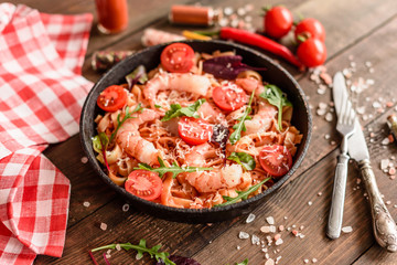 Tasty pasta with shrimp and tomato on a frying pan