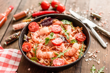 Tasty pasta with shrimp and tomato on a frying pan