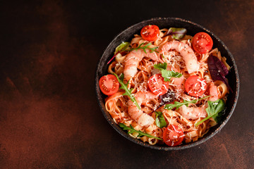 Tasty pasta with shrimp and tomato on a frying pan