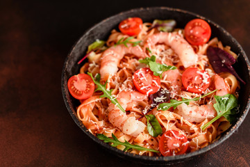 Tasty pasta with shrimp and tomato on a frying pan