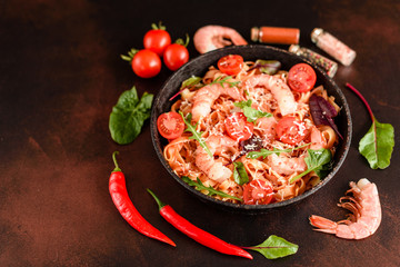 Tasty pasta with shrimp and tomato on a frying pan