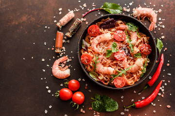 Tasty pasta with shrimp and tomato on a frying pan