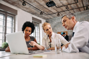 Obraz premium Multi-ethnic group of business people working on laptop during a meeting.