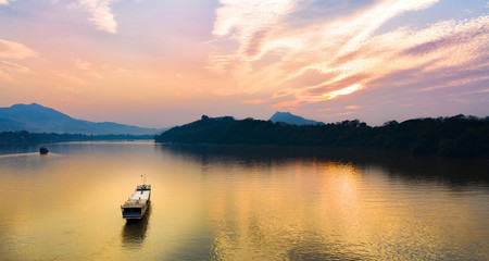 Stunning aerial view of a tourists boat sailing along the Mekong river at sunset in Luang Prabang,...