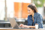 Serious woman using a laptop on a table in a park