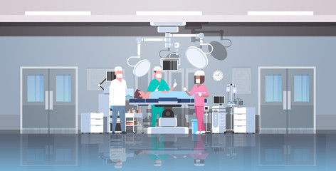 mix race surgeons team surrounding patient lying on operation table during surgery medical workers in operation room modern hospital clinic interior horizontal full length