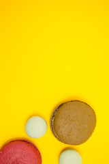 Top view of different macaroons color over yellow background