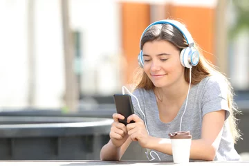 Foto op Plexiglas Teenage girl listening to music using phone in a park © Antonioguillem