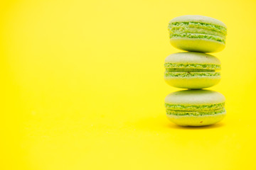 Delicious stack of green macaroons over yellow background