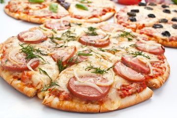 assortment of different sliced pizzas on white background