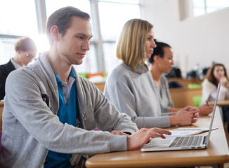 Man with laptop among students in an auditorium