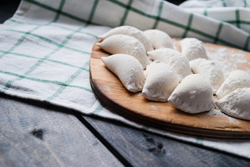 Raw dumplings sprinkled with flour on a kitchen board and a striped towel