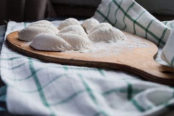 Raw dumplings sprinkled with flour on a kitchen board and a striped towel
