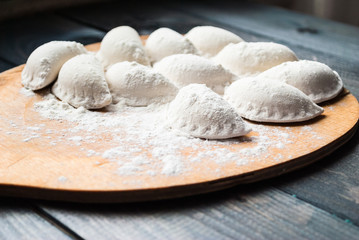 Fototapeta na wymiar Raw dumplings sprinkled with flour on a kitchen board