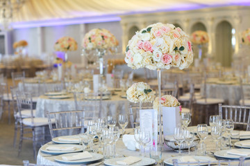 Tall white rose centerpieces at indoor wedding reception venue