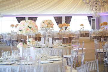 Tall white rose centerpieces at indoor wedding reception venue
