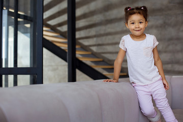 Beautiful dark-skinned child leaning on soft sofa