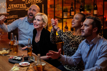 Group of friends watching tv in a cafe behind bar counter