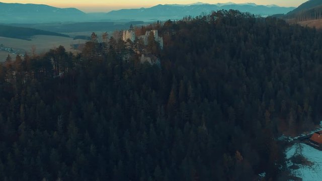 Aerial drone footage going towards forest of pine trees that surrounds castle Blatnica in the Turiec region of Slovakia