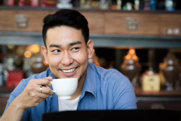 Happy Asian man drinking hot coffee in cafe, lifestyle concept.