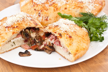 two calzone pizzas stuffed with mushrooms, ham and cheese
