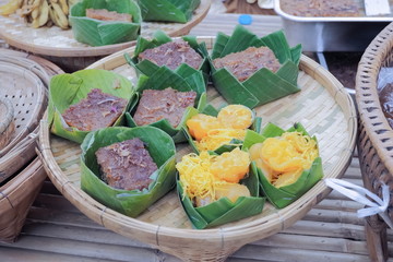 Delicious Thai Traditional Dessert Khanom Foi Thong and Thong Yip with Khanom Mo Kaeng in banana leaves container on bamboo basket.