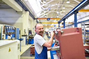 older worker in mechanical engineering - industrial factory for the production of steel gearboxes