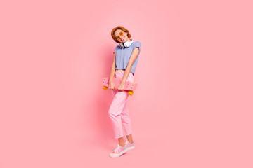 Full length body size view portrait of her she nice charming attractive lovely winsome cheerful cheery girl wearing casual holding in hands roller skate having fun isolated on pink pastel background