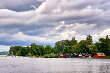 Sailboats and boathouses under dramatic clouds over the lake Schwerin. Mecklenburg-Vorpommern, Germany
