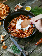 delicious fried chanterelles with sour cream straight from the forest in a pan on a wooden kitchen table