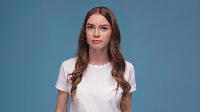 beautiful girl doing knock knock gesture and looking at camera isolated on blue