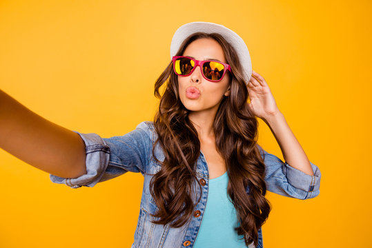 Close up photo beautiful her she wavy lady  hands arms sun hat make take selfies send air kiss instagram followers wear specs blue teal green everyday jacket clothes isolated yellow background