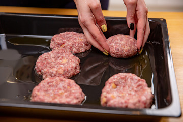 Young woman cooking meatballs or cutlets in modern kitchen