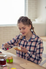 Positive delighted blonde girl looking at sandwich