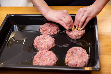 Young woman cooking meatballs or cutlets in modern kitchen