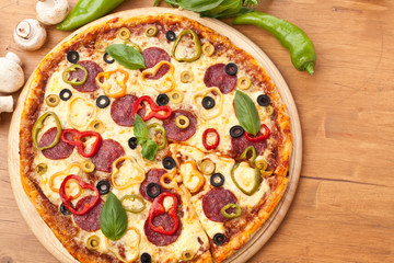 Pepperoni and Vegetable  Pizza on a cutting board with ingredients