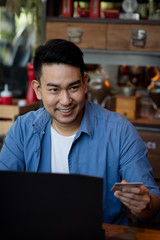Fototapeta premium Making online bank transfer, man holds a credit card while entering data in laptop