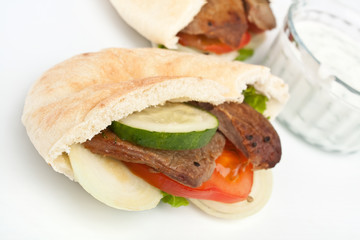 Two halves of pita bread sandwich with meat and vegetables