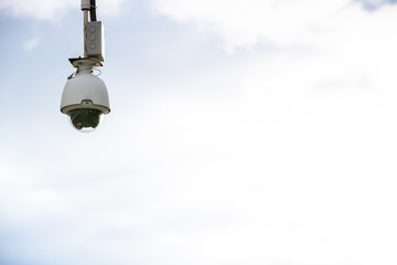 Security camera hung to monitor people in a city, isolated over blue sky and clear background with a lot of free copy space.