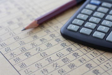 紙に書いた税金や所得や経費と計算機と鉛筆