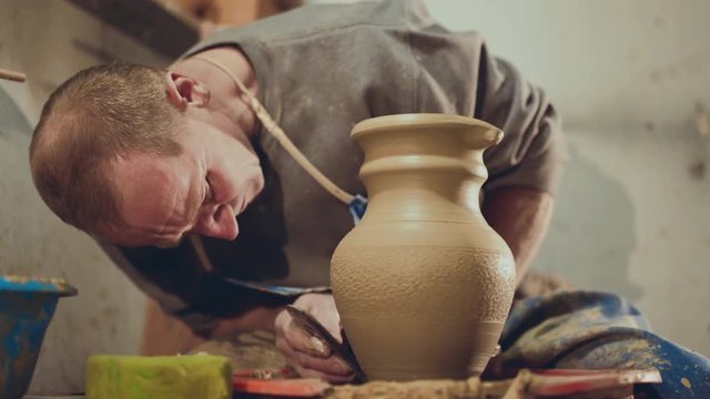 The potter making shape on clay pitcher, using tool for grind