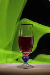 A glass of red wine on a yellowish-green abstract background.