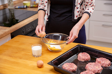 Closeup photo of woman breaking egg in glass bowl
