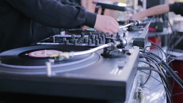 Mix and scratch, hands of a DJ on vinyl and mixer knobs. DJ playing music on a vinyl record player. DJ party stock futage