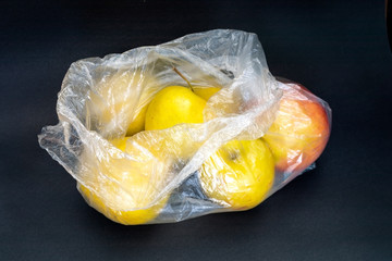 Close-up yellow apples in plastic bag on grey background. 