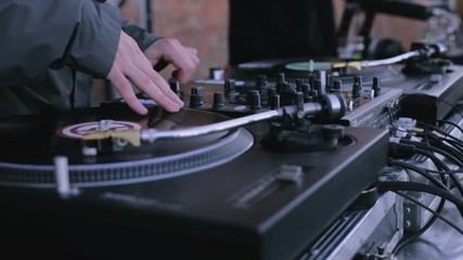Mix and scratch, hands of a DJ on vinyl and mixer knobs. DJ playing music on a vinyl record player. DJ party stock futage