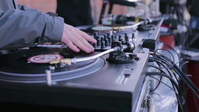 Mix and scratch, hands of a DJ on vinyl and mixer knobs. DJ playing music on a vinyl record player. DJ party stock futage