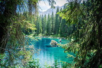 lago di carezza or karersee, a beautiful lake in the dolomites mountains surrounded by conifers, south tyrol, italy - obrazy, fototapety, plakaty