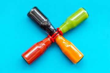 bottles with fresh carrot, tomato, apple, cucumber, lemon, pomegranate juices on blue background top view copyspace
